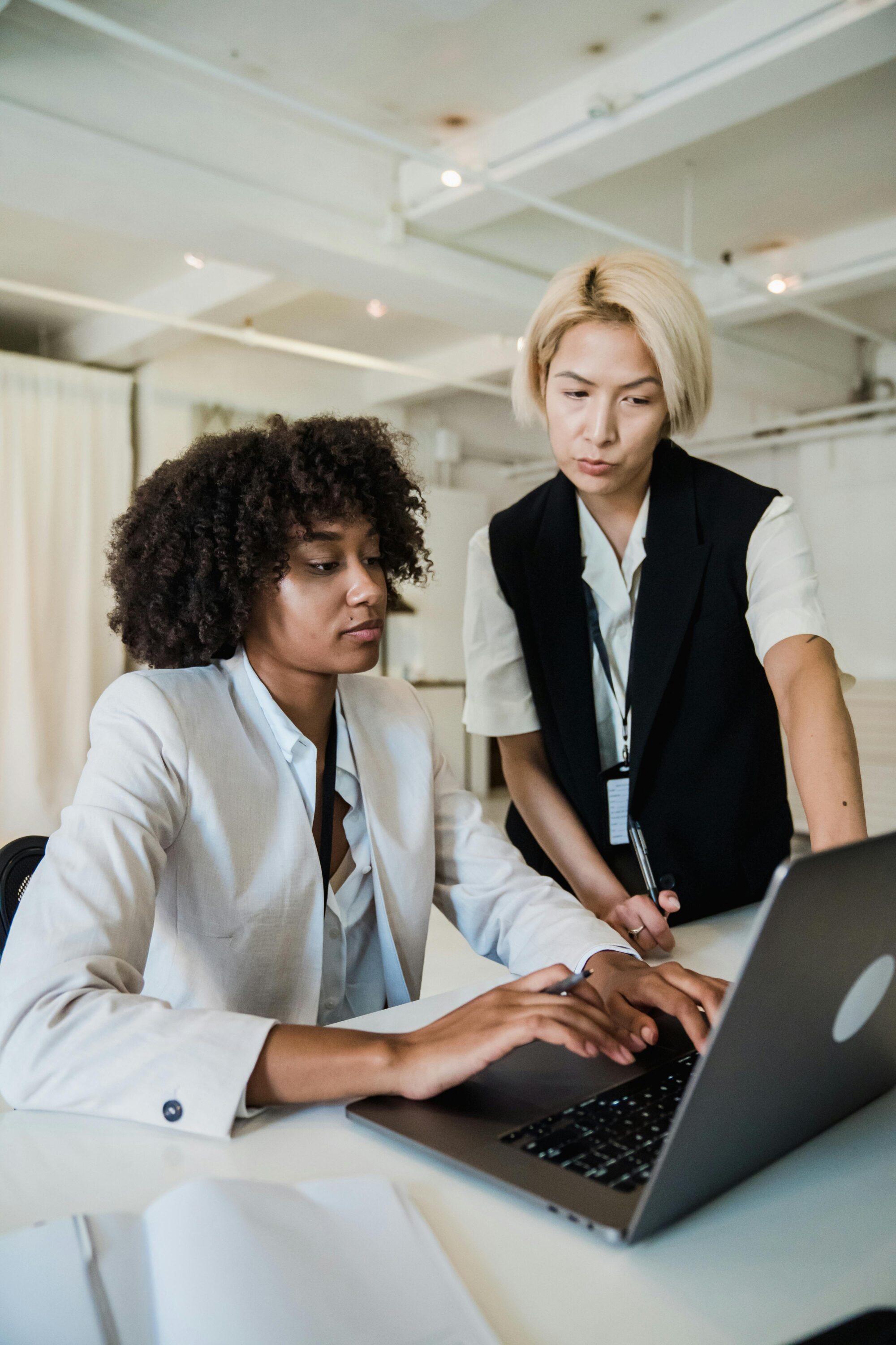 Senior specialist mentoring a young professional at a laptop in a modern office