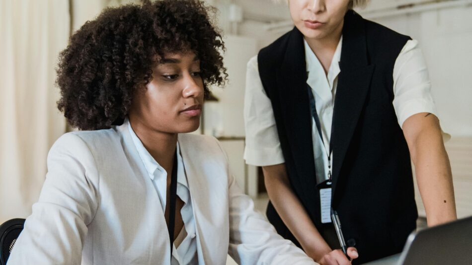 Senior specialist mentoring a young professional at a laptop in a modern office