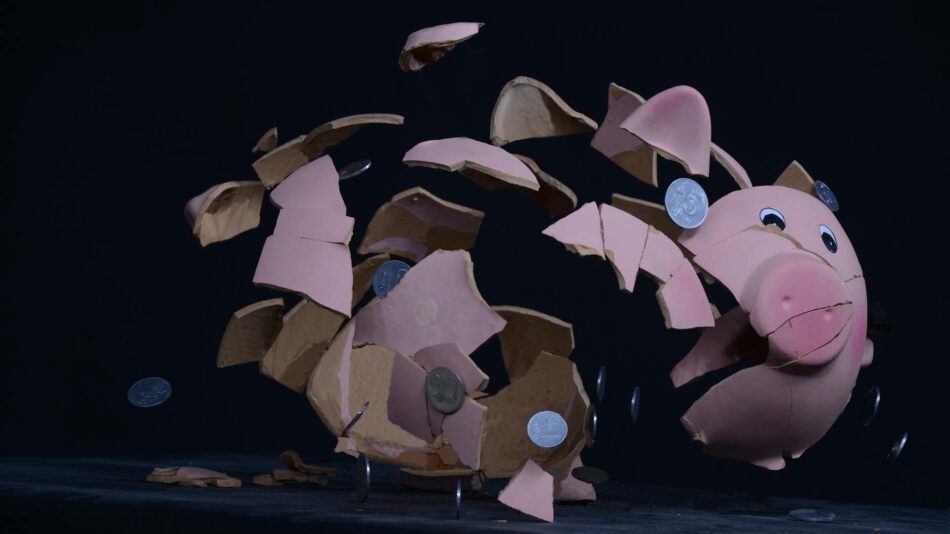 Shattered pink piggy bank with coins scattering - you cannot save yourself rich