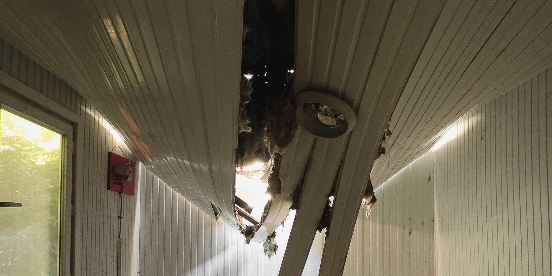 A room with a collapsed ceiling, panels hanging down and debris exposed: the damage nobody noticed until it gave way.